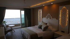 A hotel room with a large bed, a small table, and a view of the sea. - Süzer Resort Hotel (Silifke)
