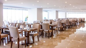A spacious dining area with multiple tables and chairs, large windows, and a polished floor. - Süzer Resort Hotel (Silifke)