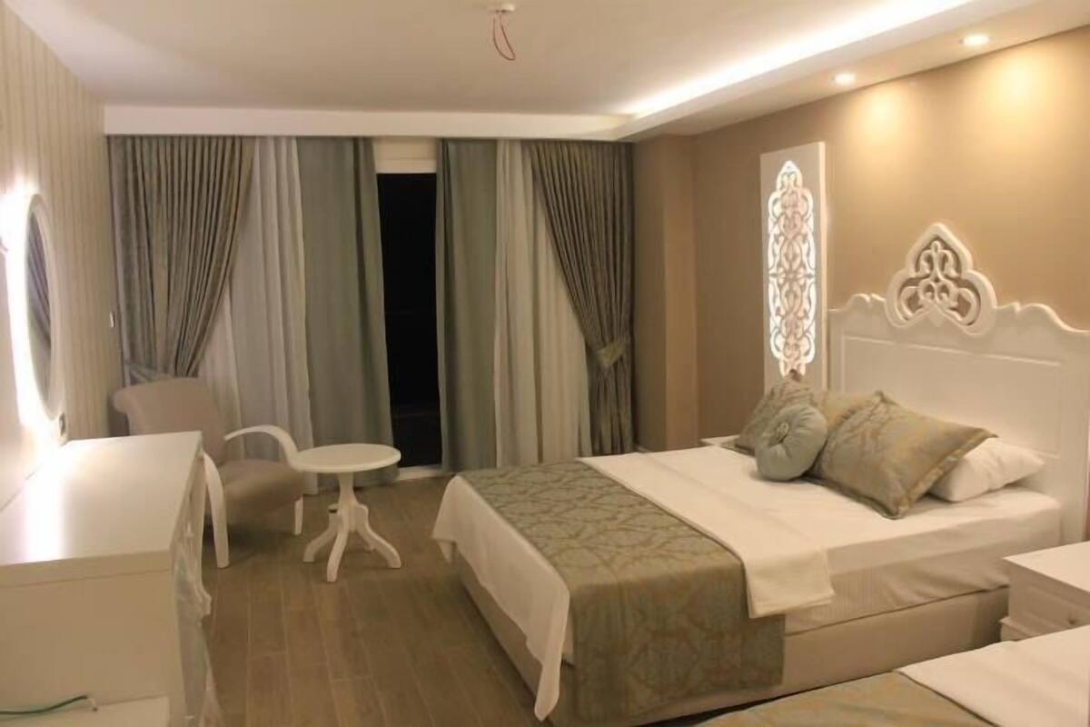 A hotel room with a bed, bedside table, chair, and a small table.