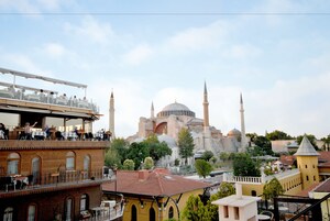 Vista di un edificio storico con numerose torri minareto e cupole, circondato da alberi e altri edifici.