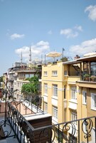 Un edificio a più piani con balconi, una moschea con minareti e un cielo blu limpido.
