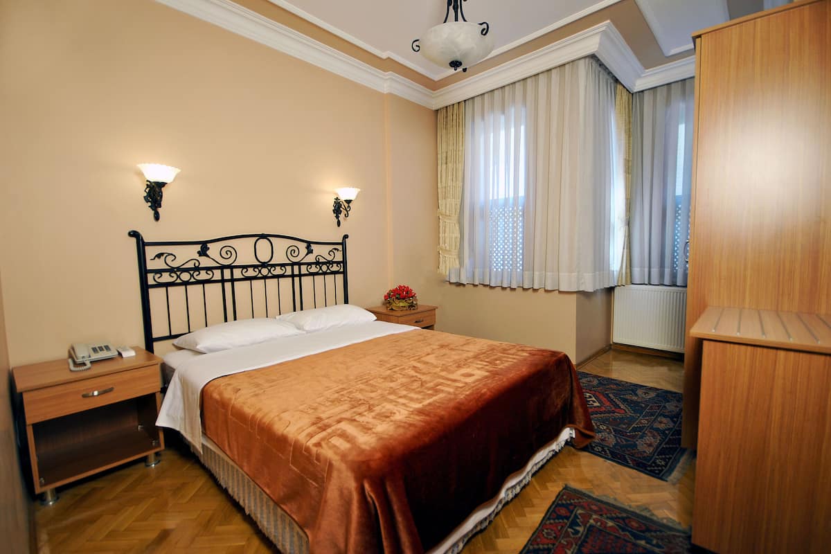 A neatly arranged bedroom with a bed, bedside table, lamp, and a window with curtains.
