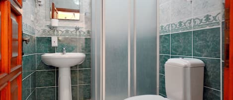 A bathroom with a white sink, toilet, and shower enclosure.