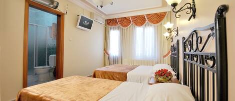 A hotel room with two beds, a shower, a TV, and a window with curtains.