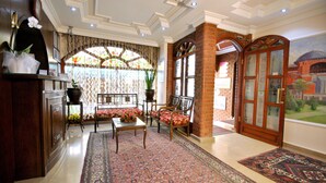 A traditional interior with a reception desk, seating area, and a view of a mural. - Side Hotel (Istanbul)