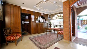 A lobby with wooden furniture, a large rug, and a brick column. - Side Hotel (Istanbul)