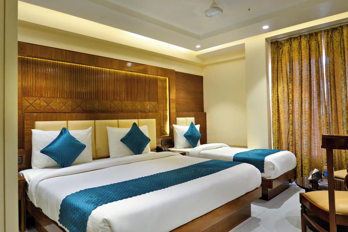 A hotel room with two beds, a wooden headboard, and a large window with curtains.