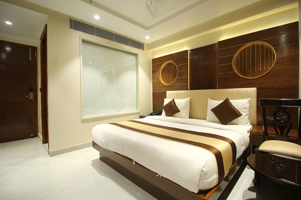 A modern hotel room with a large bed, a desk, and a view of the city.