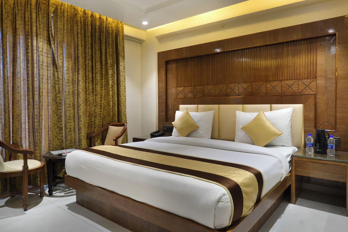 A hotel room with a large bed, wooden headboard, and a desk with a chair.
