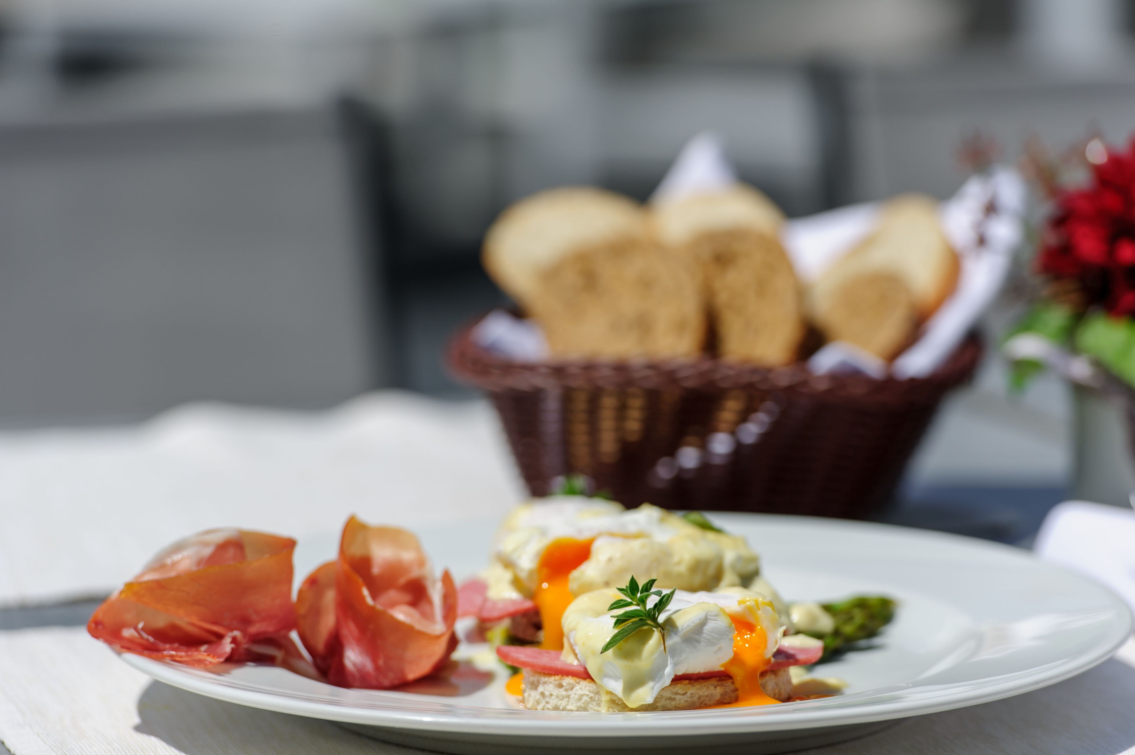 A plate of food with bread rolls in the background.