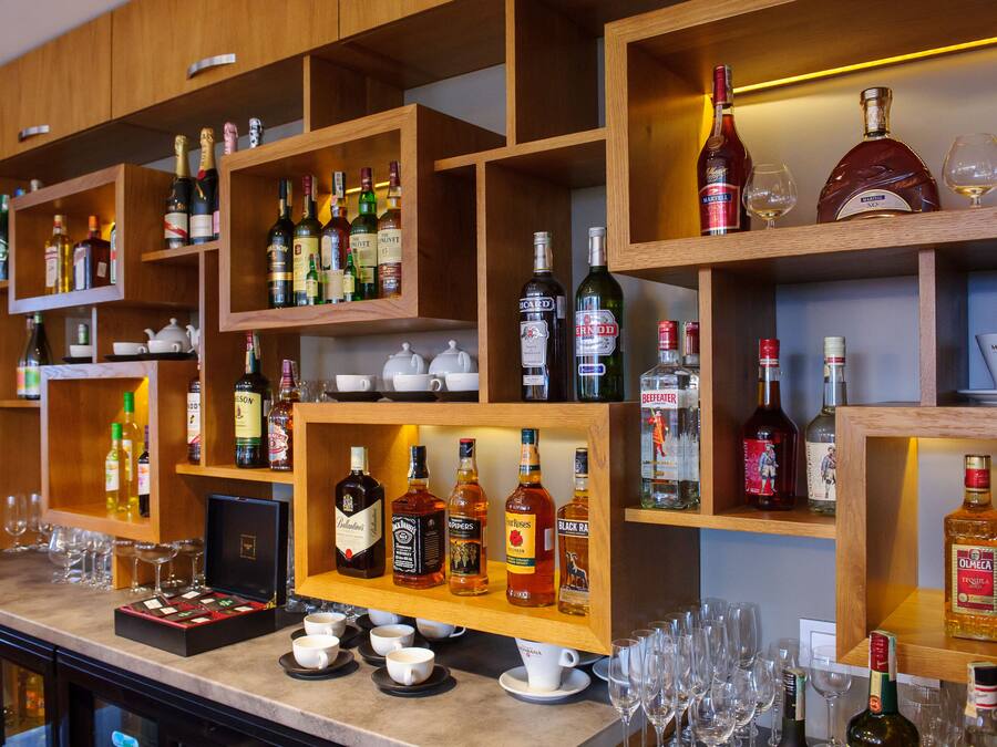 Una zona de bar con estantes llenos de botellas de licores y vasos.