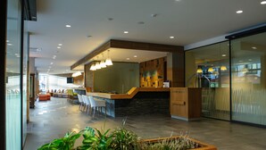 Un moderno vestíbulo de hotel con una recepción, zona de estar y una escalera.