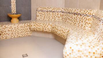Un rincón de una habitación con un sofá estampado con motivos de mosaico y un inodoro instalado en la pared.