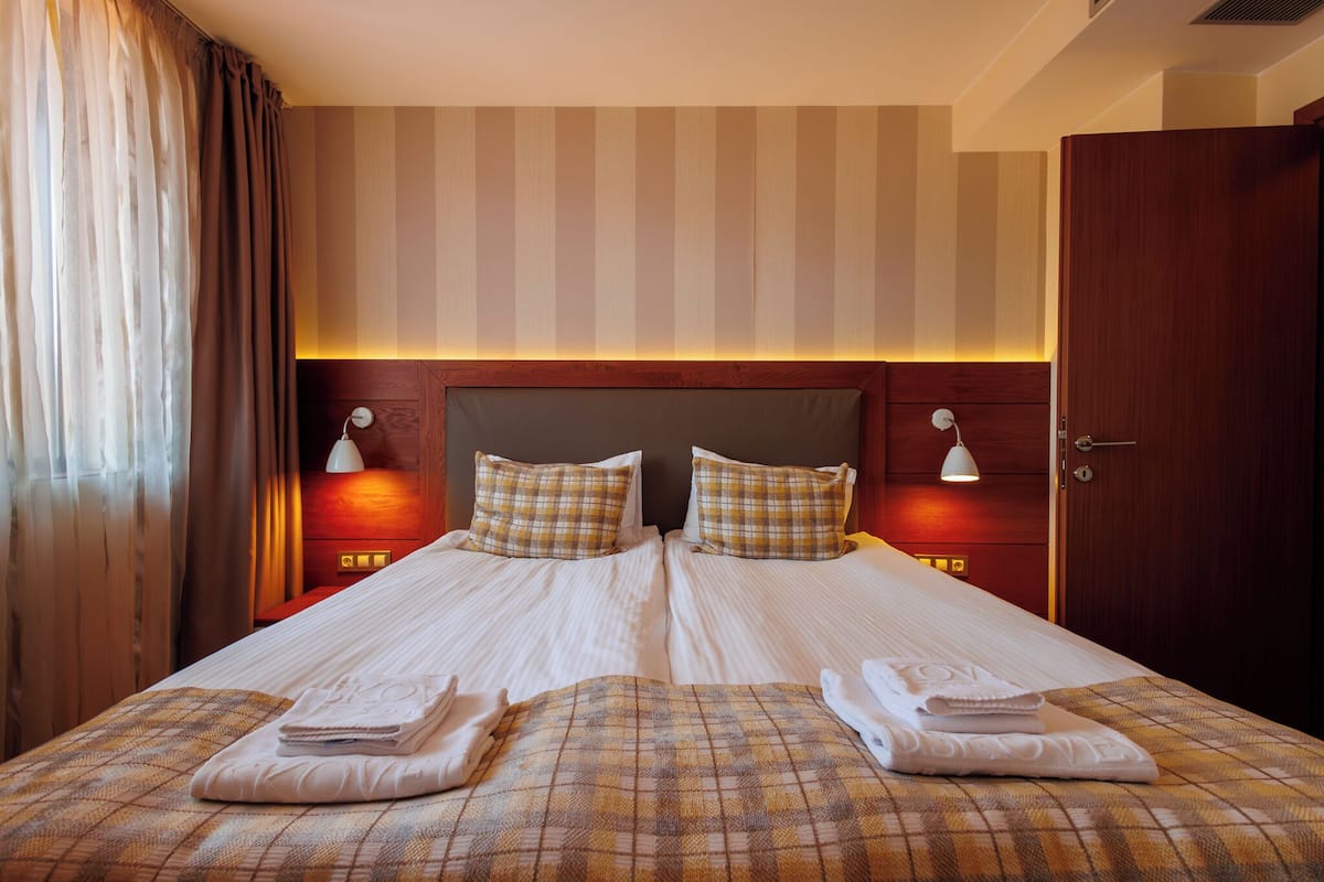 A double bed with plaid bedding, two bedside lamps, and a wooden headboard.