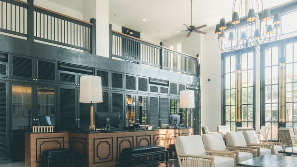 A spacious lobby with a high ceiling, a chandelier, and a seating area with chairs and a table. - Buri Siri Hotel (Chiang Mai)