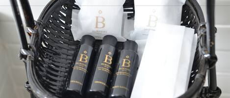 A black wicker basket containing three bottles with 'BURISI' labels and white napkins with 'BURISI' logos.