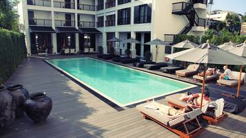 Una piscina al aire libre, sillones reclinables de piscina