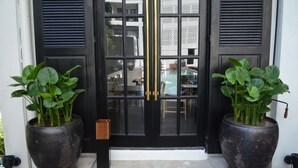 A black door with glass panels and two large potted plants on either side. - Buri Siri Hotel (Chiang Mai)