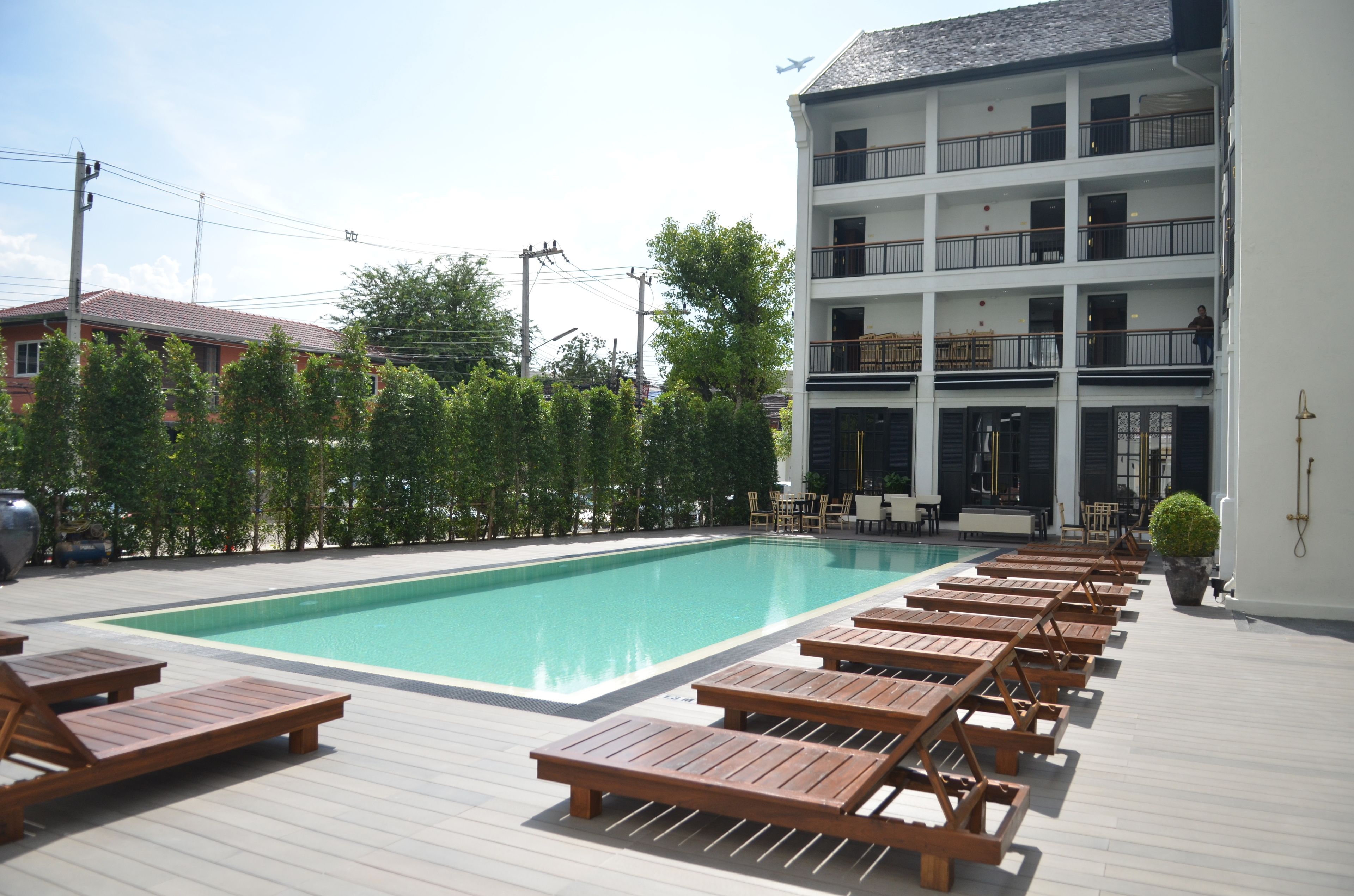 Una piscina con sillas de descanso y un edificio con varios balcones.