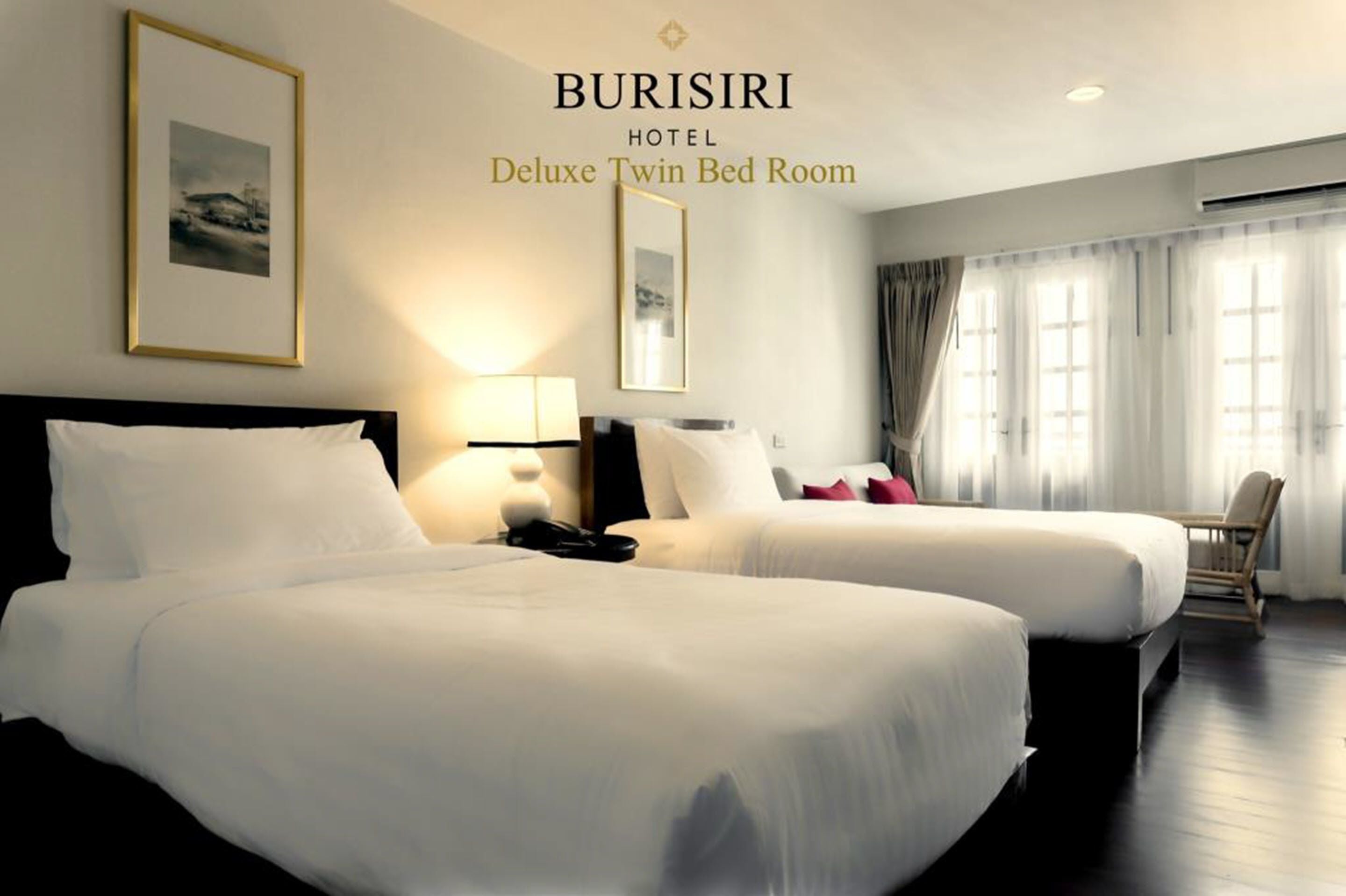 Une chambre de luxe avec deux lits jumeaux à l’hôtel Burisiri, comprenant deux lits, des lampes de chevet, une chaise et une grande fenêtre avec des rideaux.