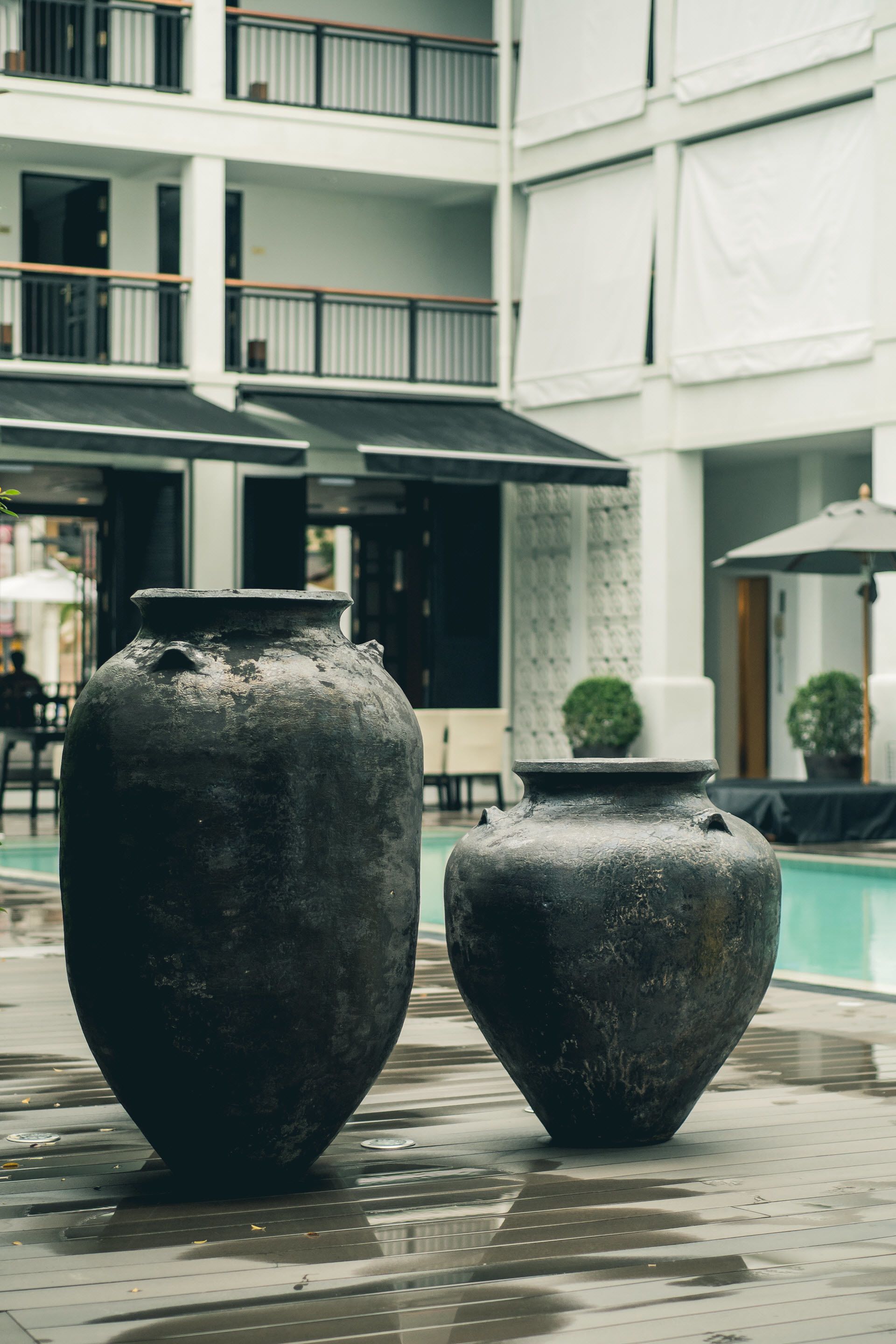 Two large vases near a poolside area with a building in the background.