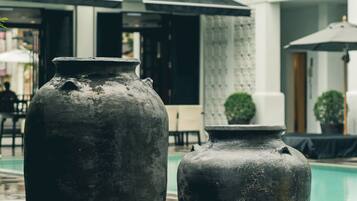 Two large vases near a poolside area with a building in the background.