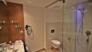 Un baño moderno con ducha envuelta en vidrio, lavamanos blanco y un inodoro.