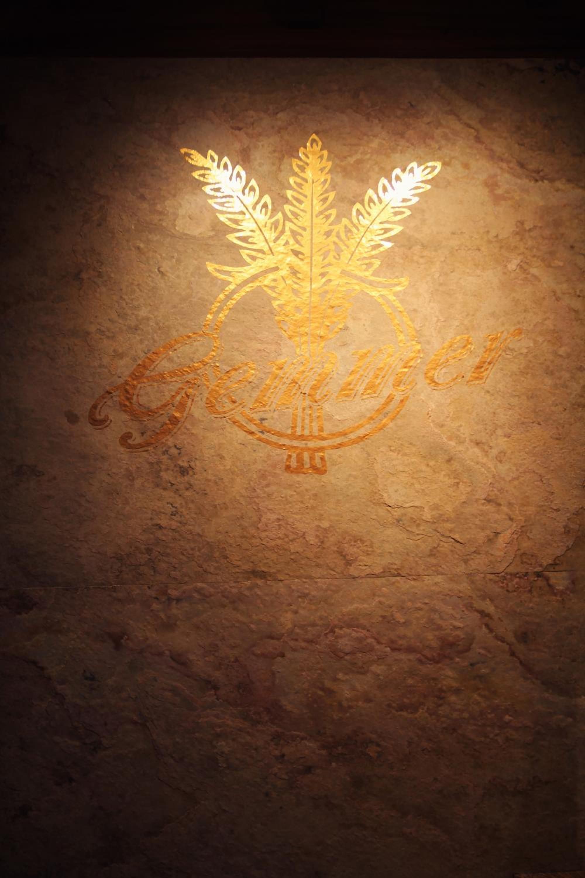 A textured surface with a golden emblem featuring a laurel wreath and a shield.