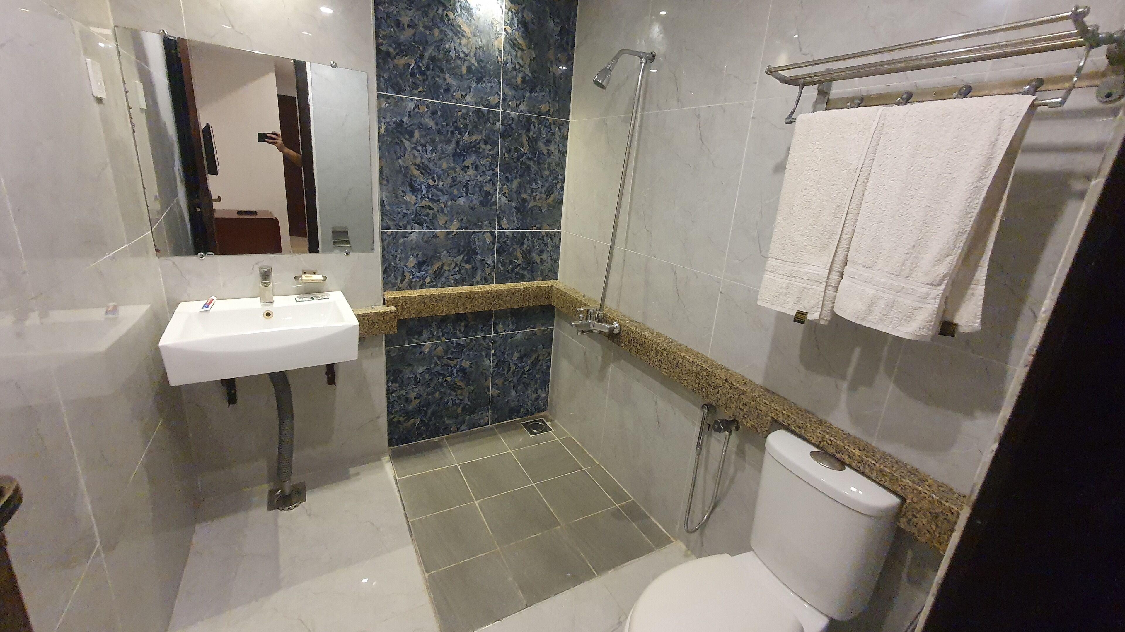 Un baño moderno con un lavamanos blanco, ducha e inodoro.