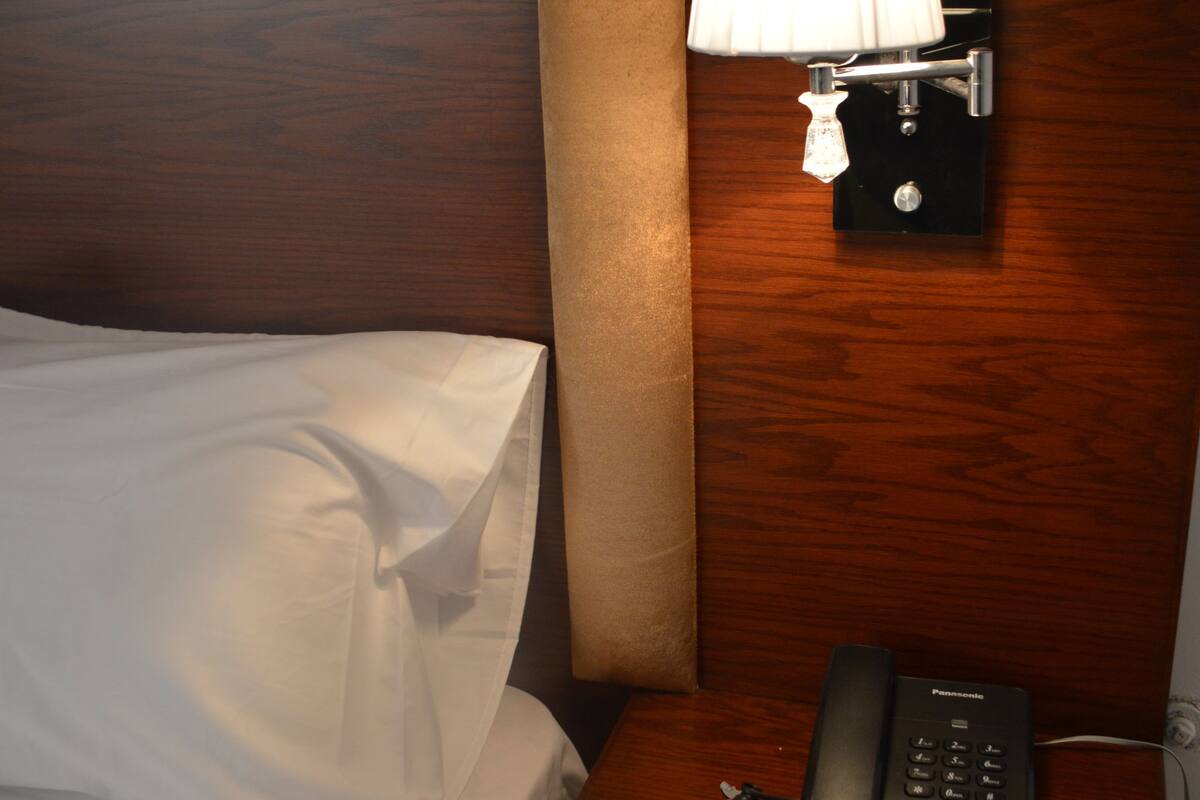 Une chambre d’hôtel avec un lit, une table de chevet, une lampe et un téléphone.