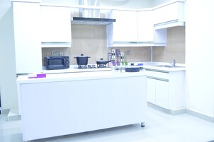 Una cocina moderna con armarios blancos, un microondas integrado, una estufa a gas y varios utensilios de cocina.