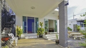 A modern house with a patio, outdoor seating, and potted plants. - Baan Taradon By Puppap (Hua Hin)