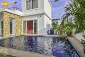 Une maison moderne à deux étages avec une piscine située dans le jardin avant.