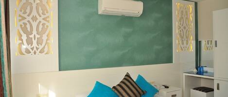 A hotel room with a bed, a bedside table, a nightstand, a mirror, and a wardrobe.