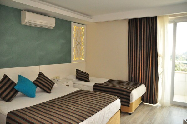 Habitación de hotel con dos camas, una ventana con cortinas, un equipo de aire acondicionado y un panel decorativo en la pared.