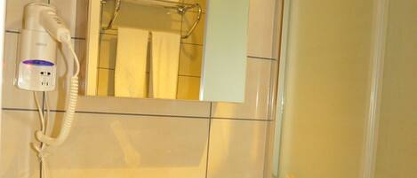 A bathroom with a white sink, a mirror, and a hairdryer on the wall.