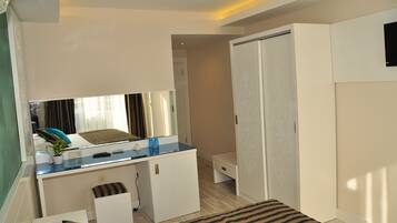 Een kleine hotelkamer met een bed, een bureau met computer, een zithoekje en een kledingkast.