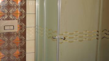 Un baño con cabina de ducha de vidrio, inodoro y azulejos con diseño.