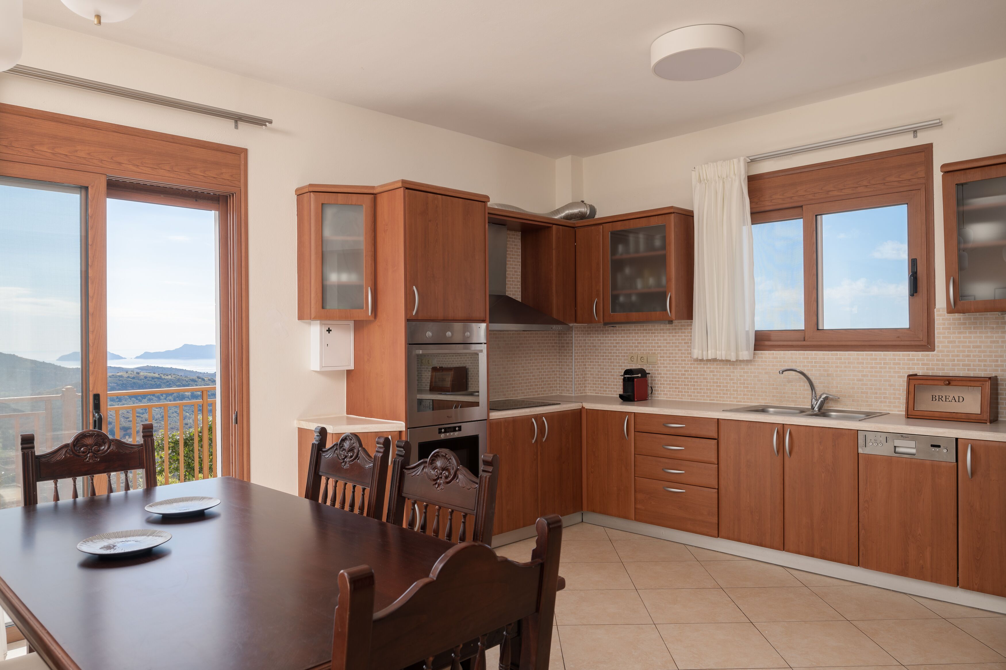A modern kitchen with wooden cabinets, a dining table, and a view of the outdoors.