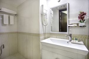 Un baño con lavamanos blanco, un espejo y una ducha.