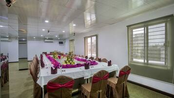 Un salón de conferencias con una larga mesa dispuesta para una reunión, equipado con sillas y un proyector.
