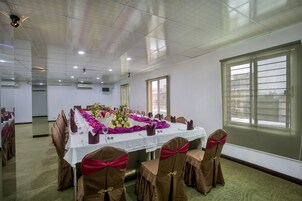 Un salón de conferencias con una larga mesa dispuesta para una reunión, equipado con sillas y un proyector.
