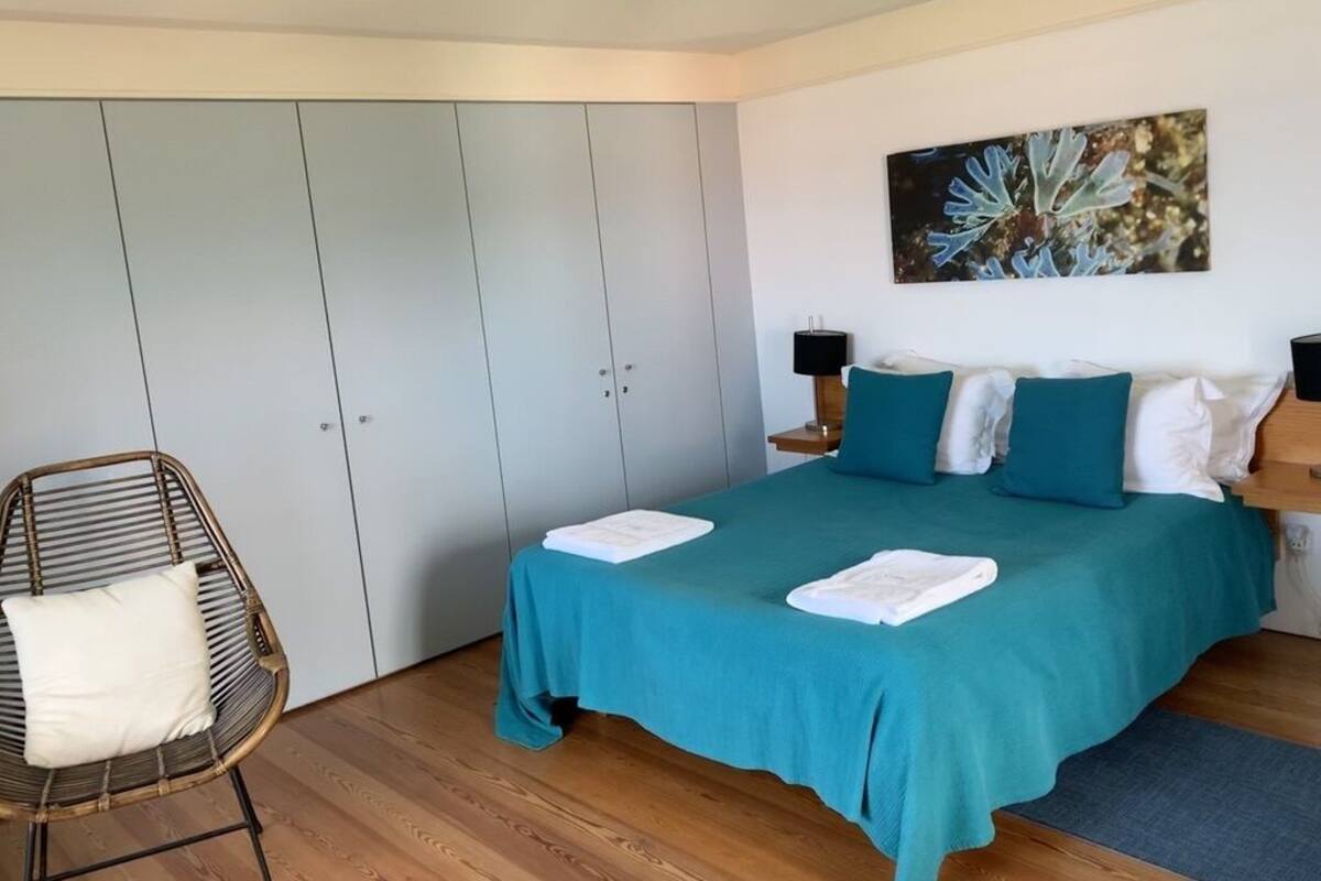 Une chambre à coucher avec un lit, une chaise, une armoire et un tableau au mur.