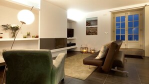 A modern living room with a sofa, a green armchair, a TV, and a fireplace. - A Casa do Ouvidor (Sao Roque do Pico)