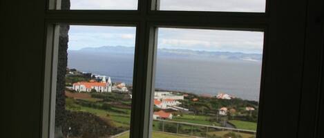 Ein Fenster mit Blick auf eine Küstenlandschaft, einschließlich Gebäude und Grünflächen.