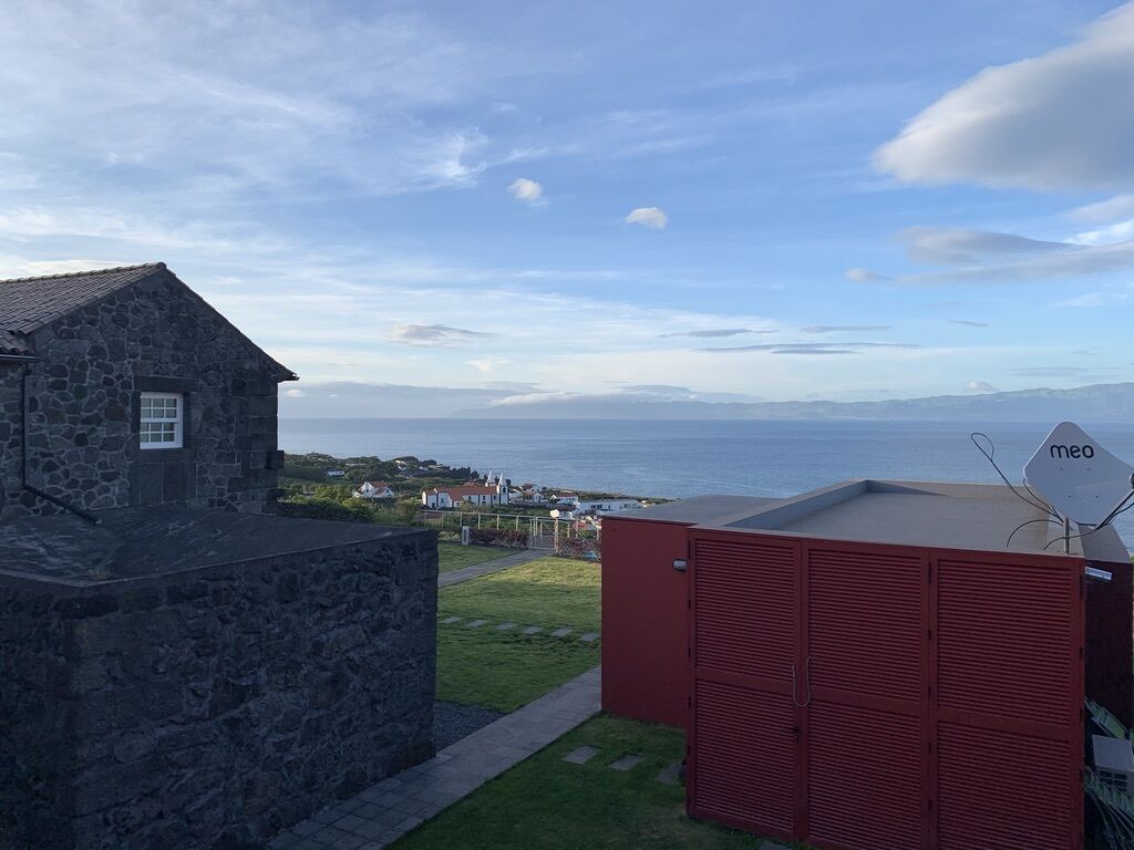A stone building with a view of the sea, a red shed, and a 'meo' sign.