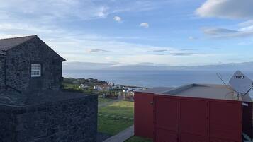 A stone building with a view of the sea, a red shed, and a 'meo' sign.