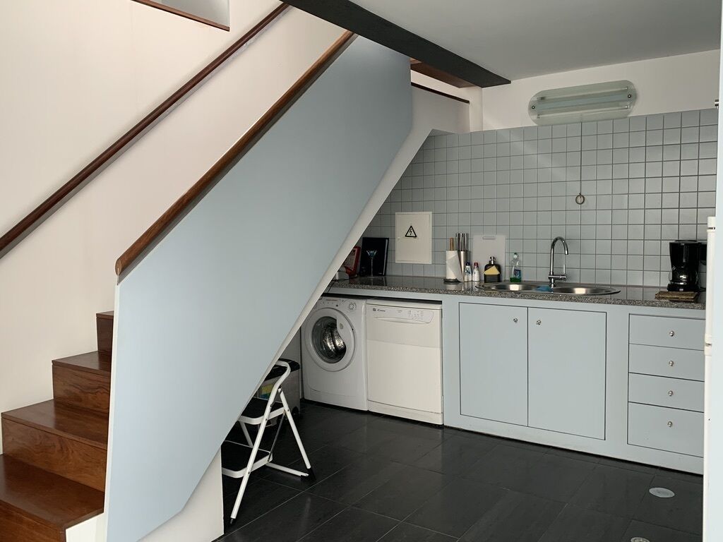 A modern kitchen with a built-in washing machine, a coffee maker, and a sink.