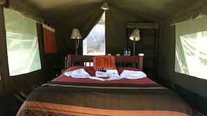 A tent-style room with a bed, two lamps, and a window.