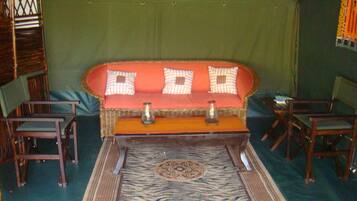 A room with a wooden sofa, two chairs, a small table, and a patterned rug.
